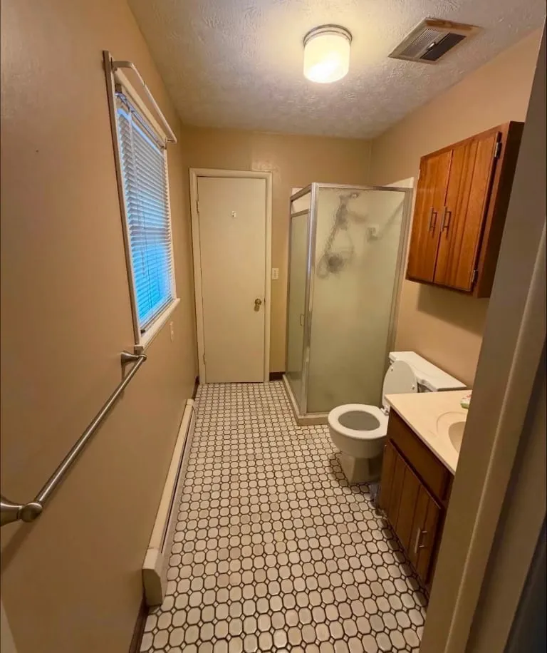 Before: A dated hall bath taken down to the studs and rebuilt with a marble-look tile shower, black-frame glass, LED mirror and a quartz-topped vanity.